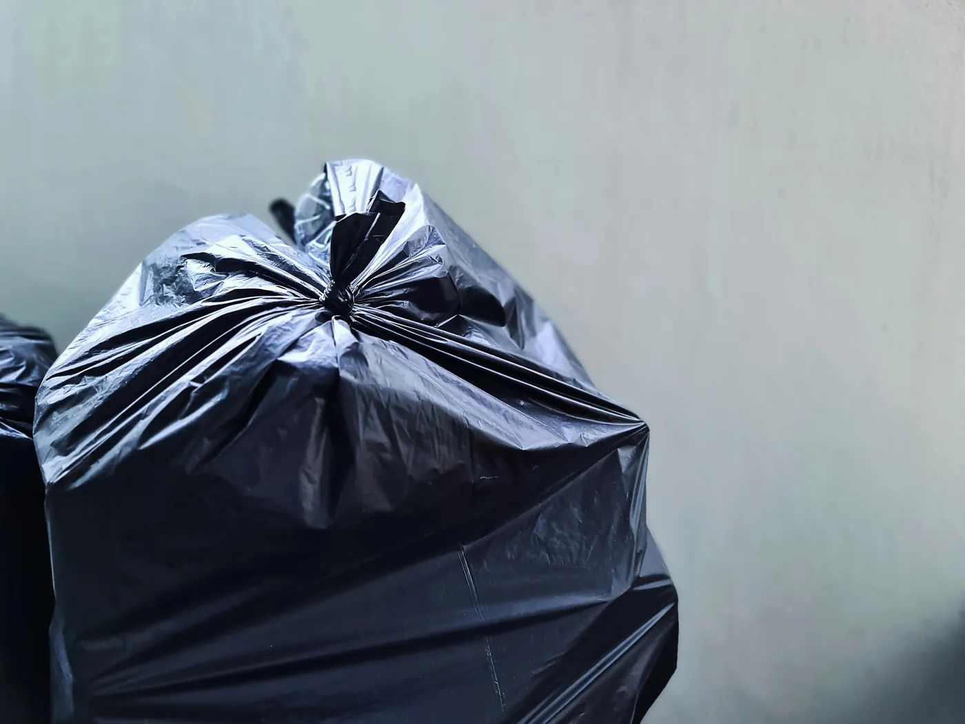 Black household trash bag set out for weekly residential pickup